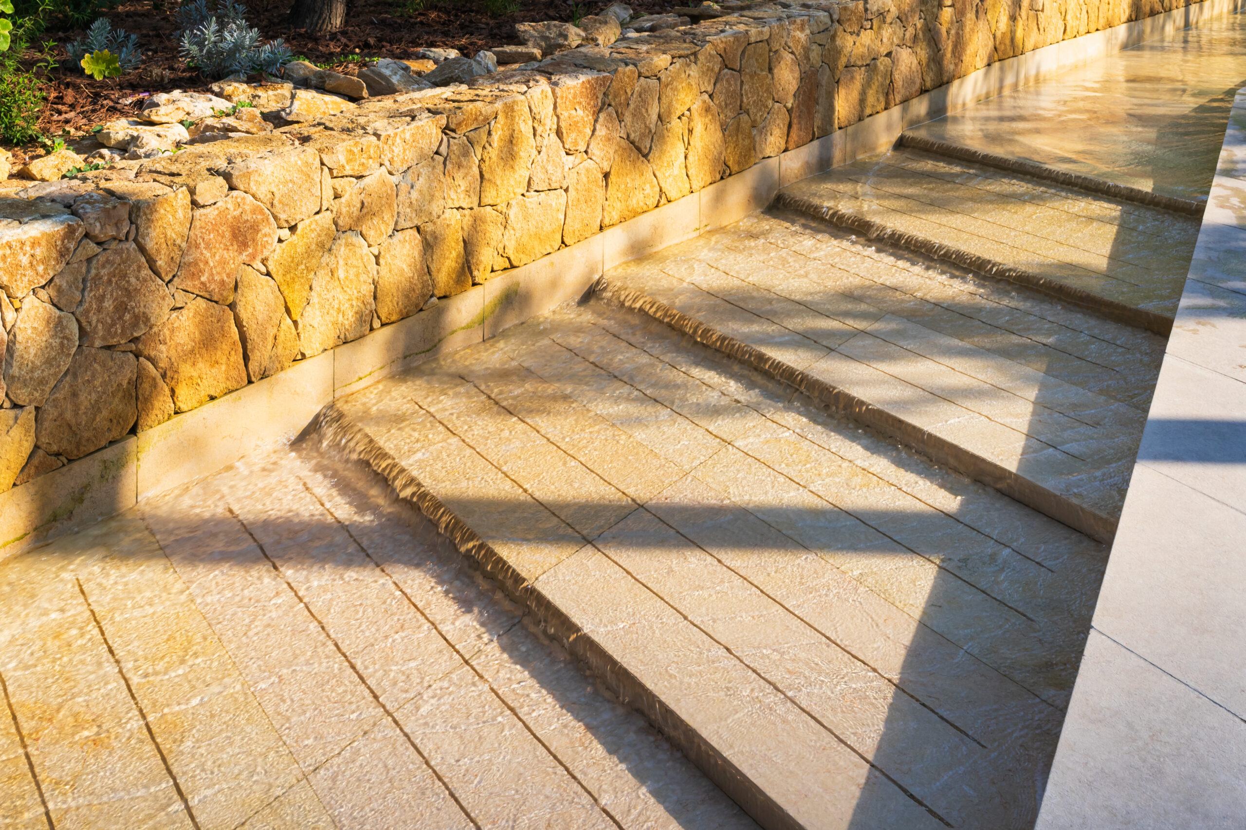 Modern luxury water feature with stone steps fountain in a park of Monaco under bright Mediterranean sunlight in summer